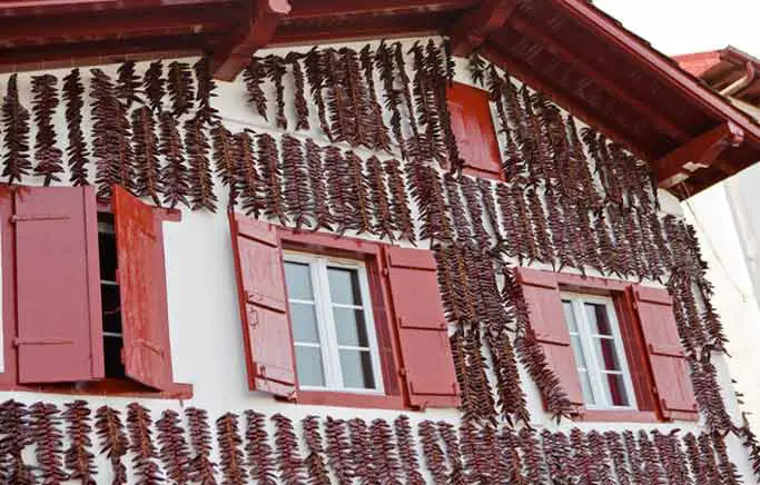 A house with red shutters in Espelette is covered with peppers hanging to dry.