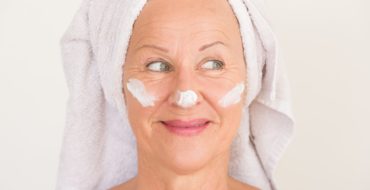 Mature woman with face cream for after summer skin treatment