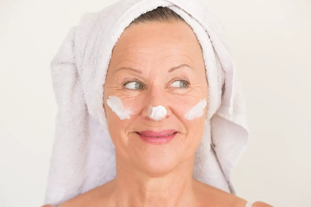 Headshot of mature woman with face cream for post-summer skin treatment