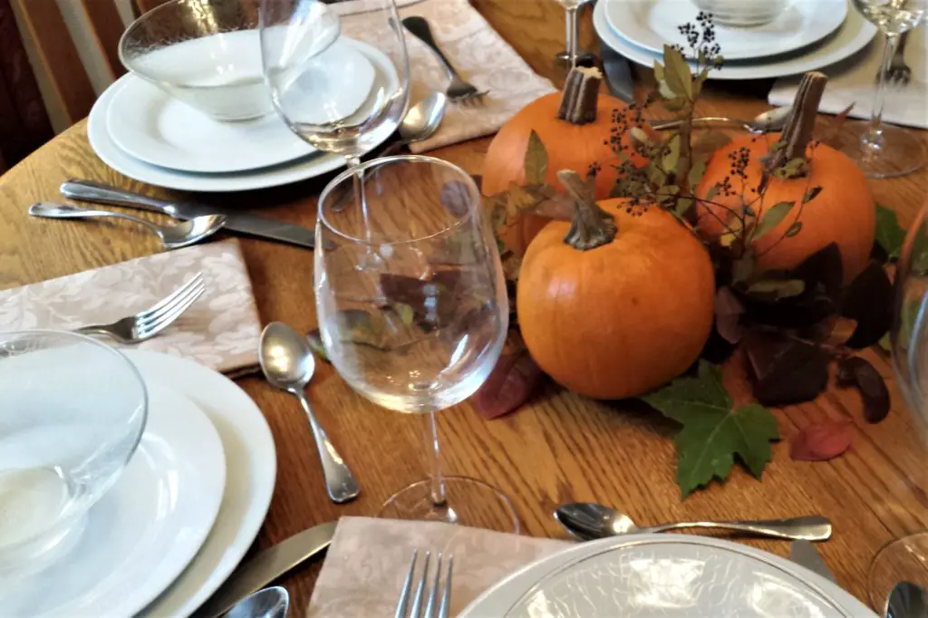 Thanksgiving centerpiece of three pumpkins on a bed of fall leaves
