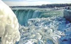 View of frozen ice formations at Niagara Falls in white, blue and green