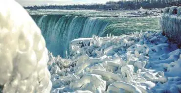 View of frozen ice formations at Niagara Falls in white, blue and green