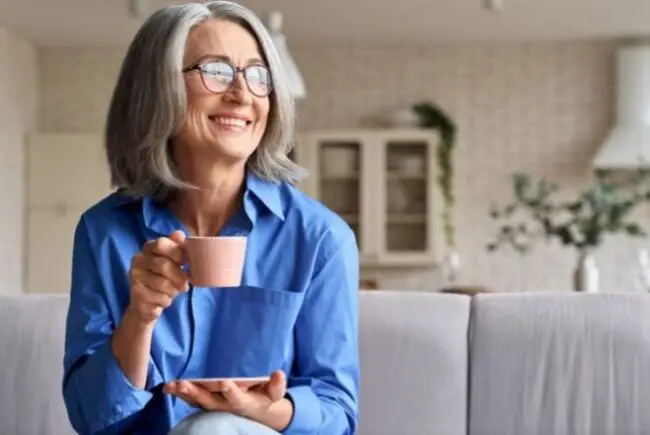 Mature woman in blue blouse drinking tea