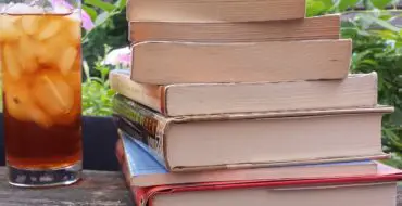 Stack of books with glass of iced tea