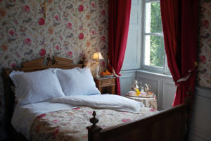 Bedroom with fabric wall covering and red draperies Chateau de la Barbee