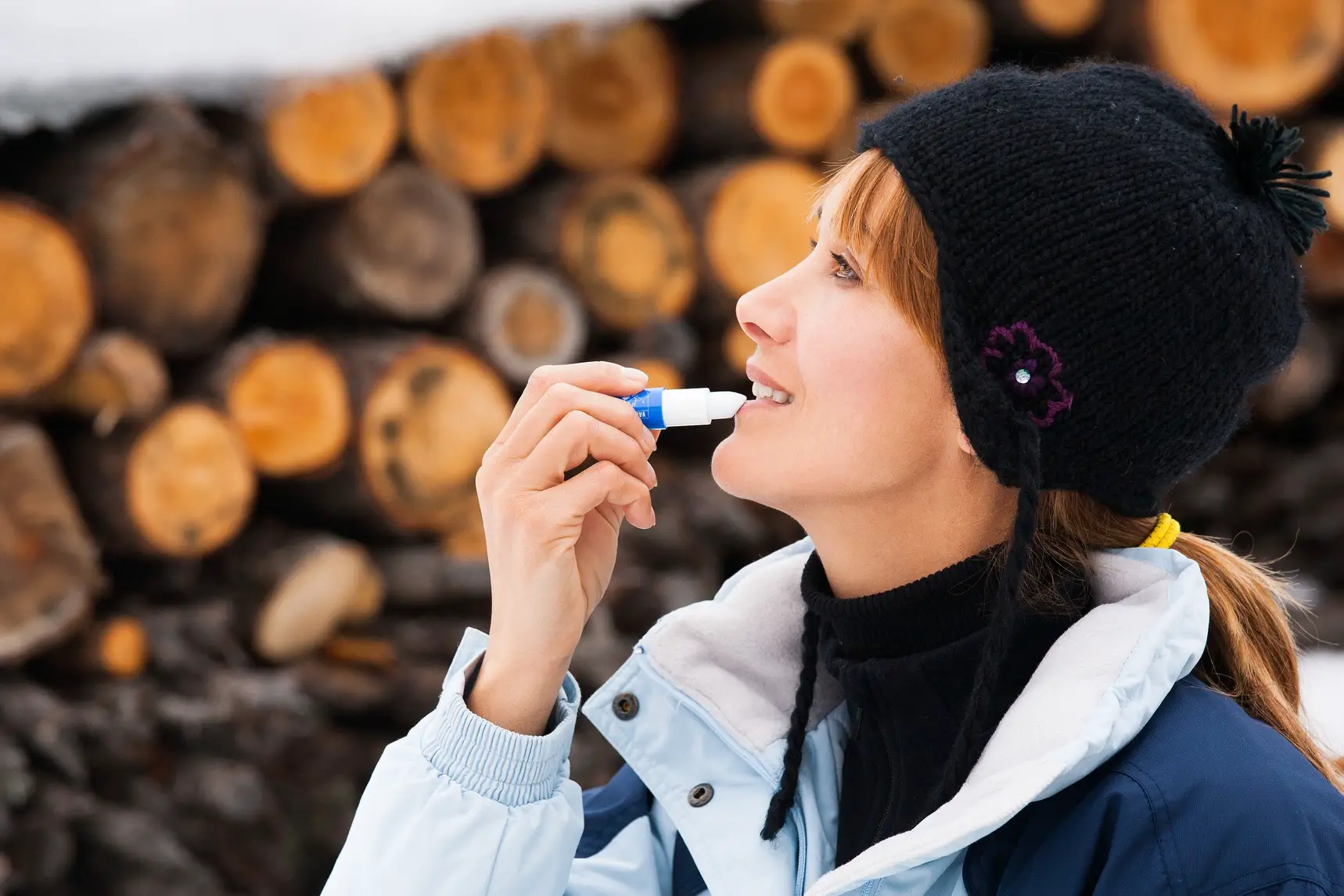 Woman applying lip balm in winter
