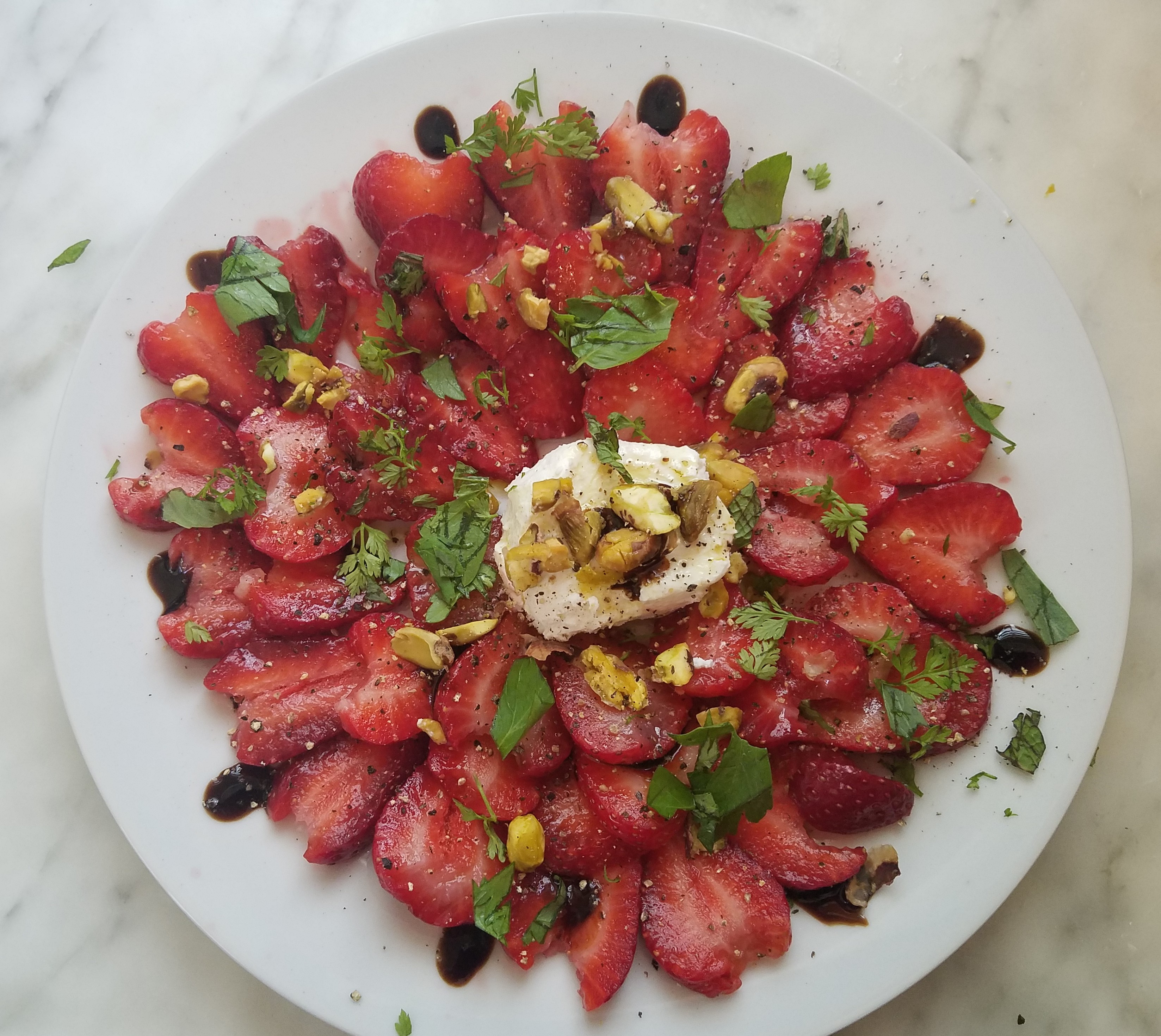 Strawberries sliced thin, arranged in rosette shape around mound of goat cheese