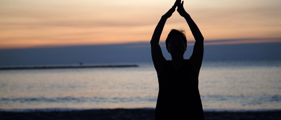 Woman doing yoga on beach at sunrise