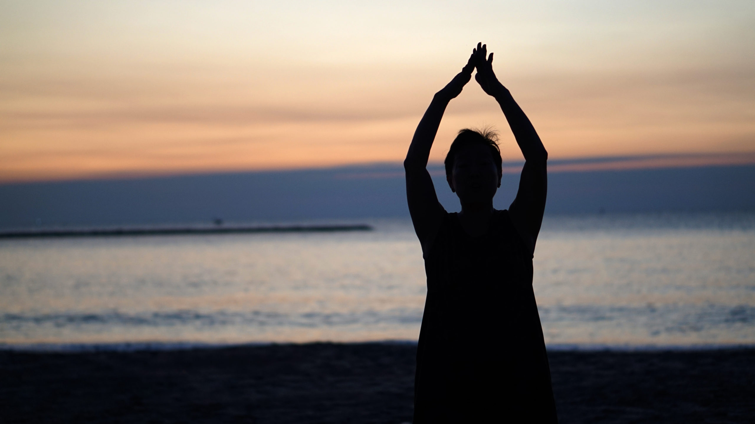 Woman doing yoga on beach at sunrise