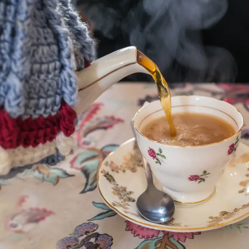 Tea being polured into a cup with milk