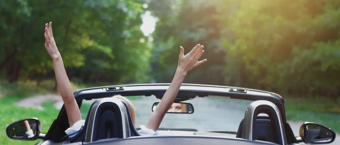 Woman waves arms in convertible