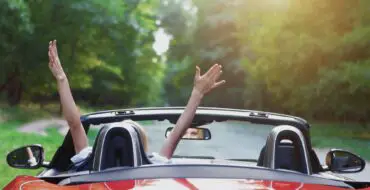 Woman waves arms in convertible