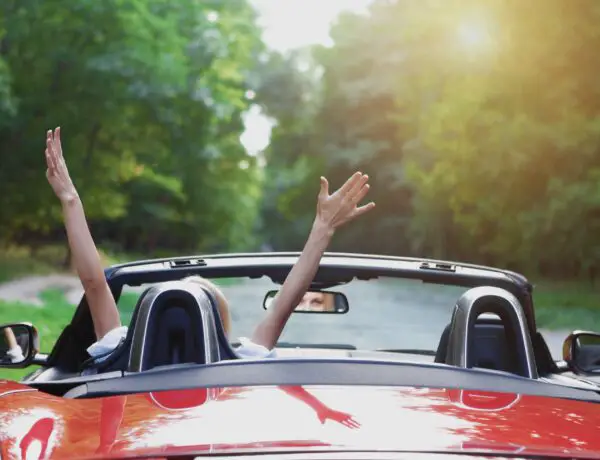 Woman waves arms in convertible