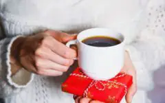 Woman holding cup of coffee and gift package