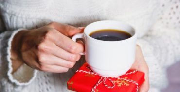 Woman holding cup of coffee and gift package