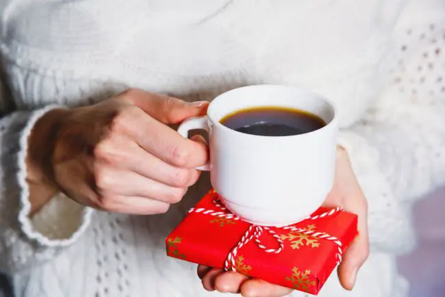Woman holding cup of coffee and gift package