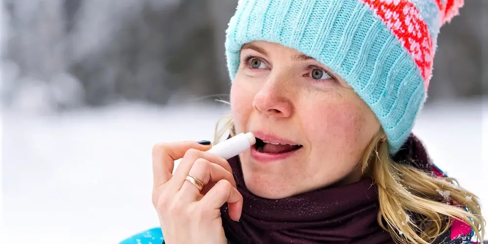 60ish woman applying lip balm in winter