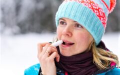 60ish woman applying lip balm in winter