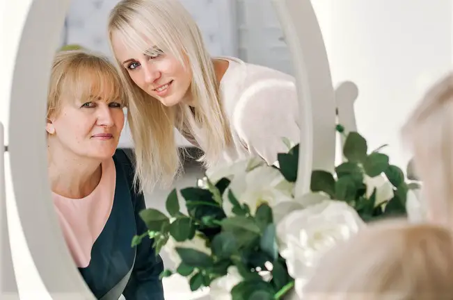 Senior mother and adult daughter looking in mirror