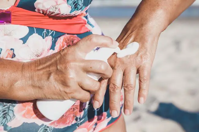 Woman over 60 applying sunscreen