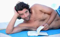 Man on beach towel reading book