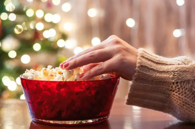 Woman reaching into popcorn bowl