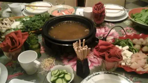Table with hot pot and ingredients for cooking