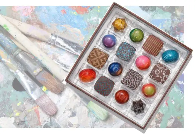 Box of gourmet chocolates with art in background