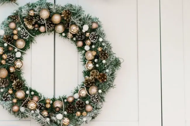 Christmas wreath with gold trim hanging on door