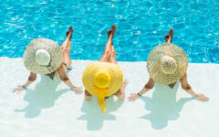Three women wearing large straw hats in swimsuits for women over 60