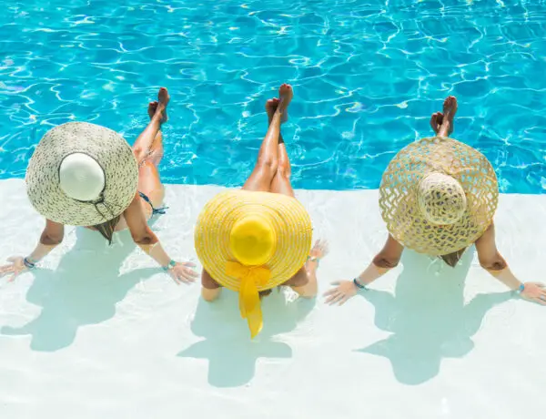 Three women wearing large straw hats in swimsuits for women over 60