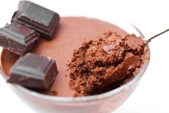 Chocolate mousse in a clear glass with three tablets of dark chocolate