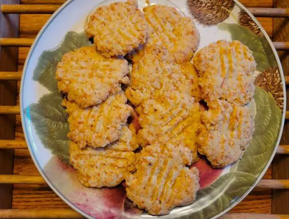 Plate with crispy cheese crackers on wood table