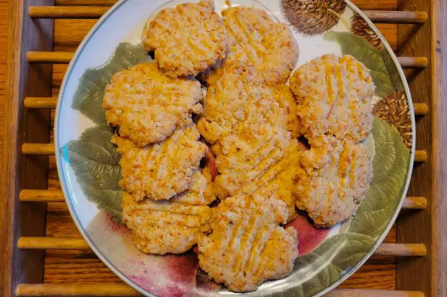 Plate with crispy cheese crackers on wood table