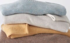 Stack of cashmere sweaters in light blue, cream, pale yellow and chestnut