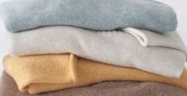 Stack of cashmere sweaters in light blue, cream, pale yellow and chestnut