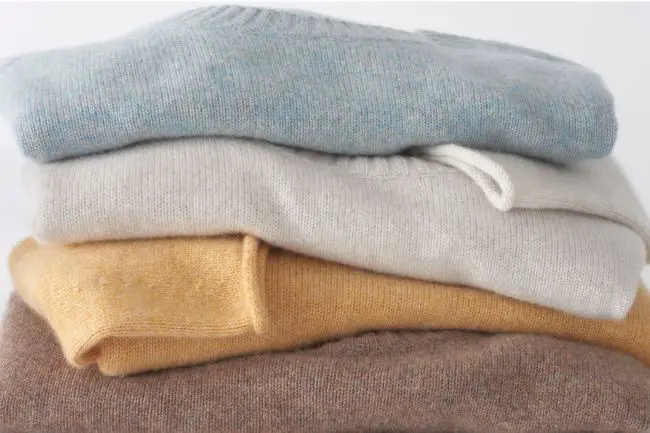 Stack of cashmere sweaters in light blue, cream, pale yellow and chestnut